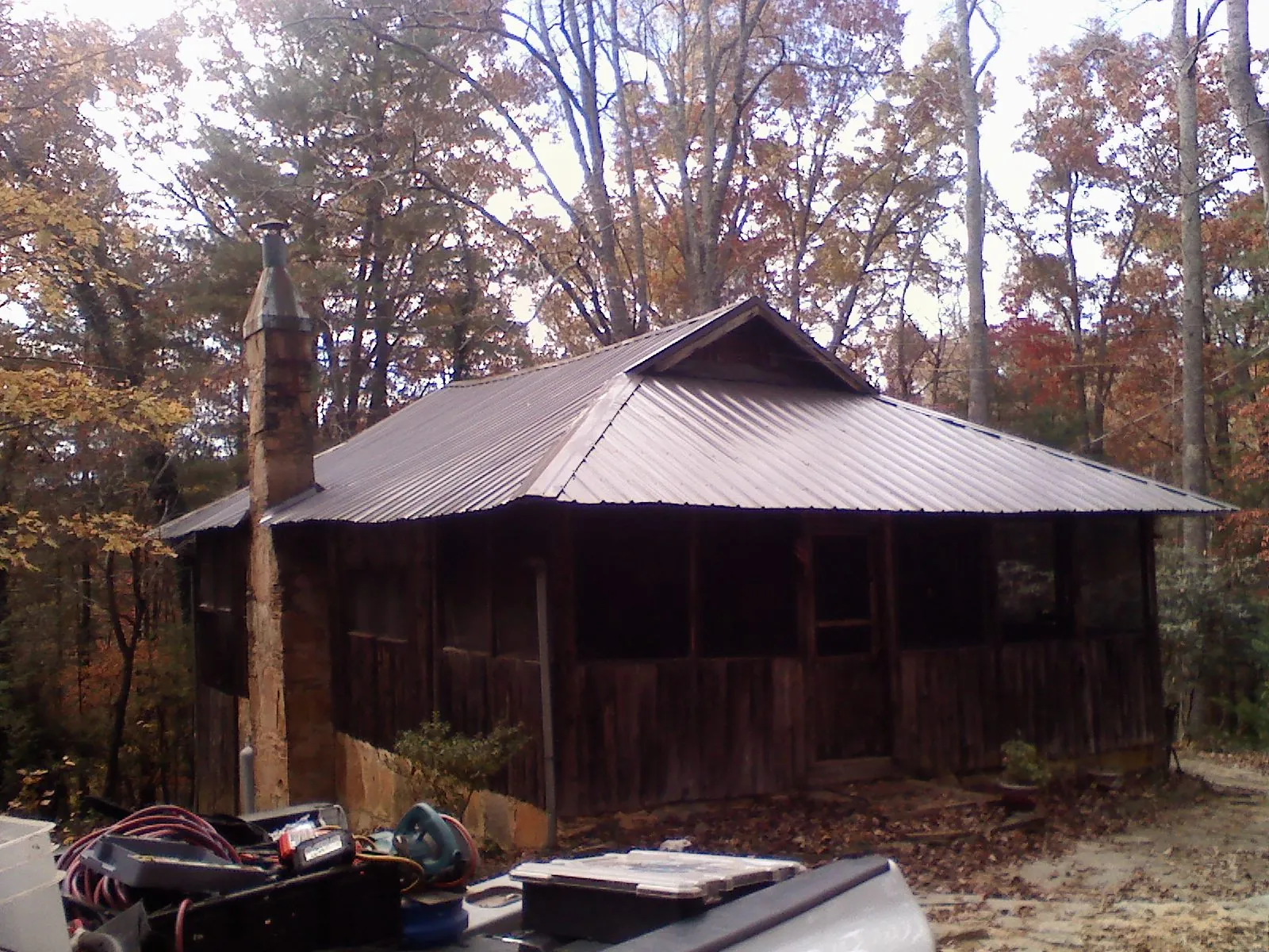 Brown metal hip roof on an old cabin with a stone chimney in Bristol